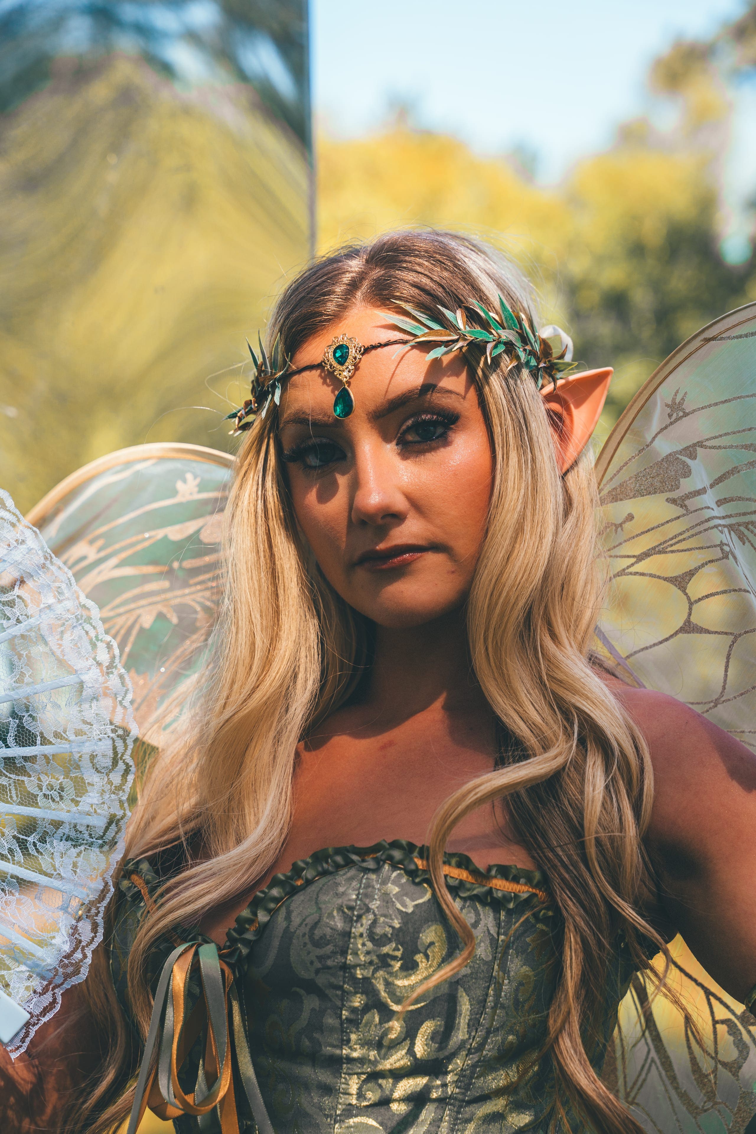 The Bloomkeeper, guardian of the Secret Garden: gossamer wings, a gold leaf headpiece and a green corset, photographed in the pines.